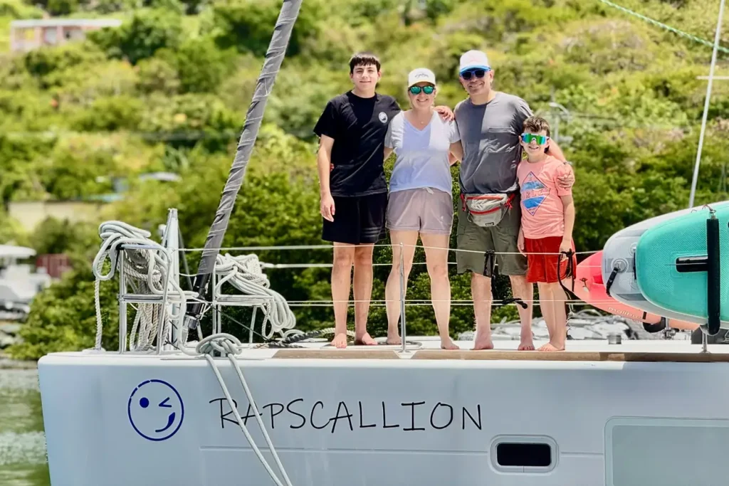 Family standing on a catamaran deck during a relaxed family yacht charter in the Caribbean.