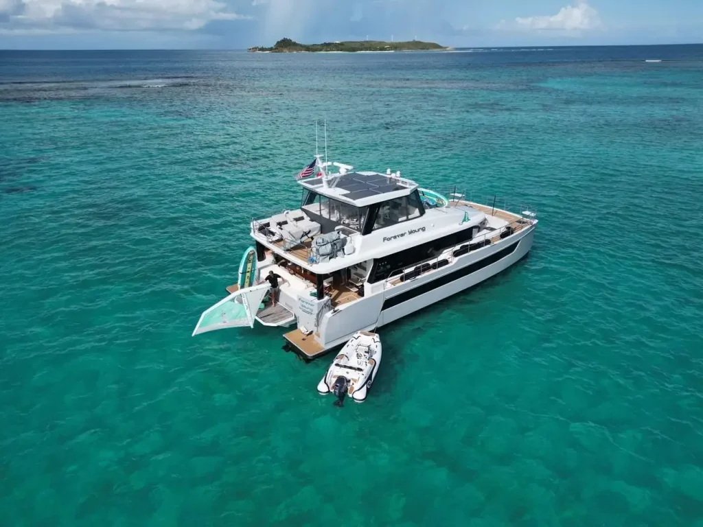 Power Catamaran Charters yacht anchored in turquoise Caribbean water with a tender and paddleboards.